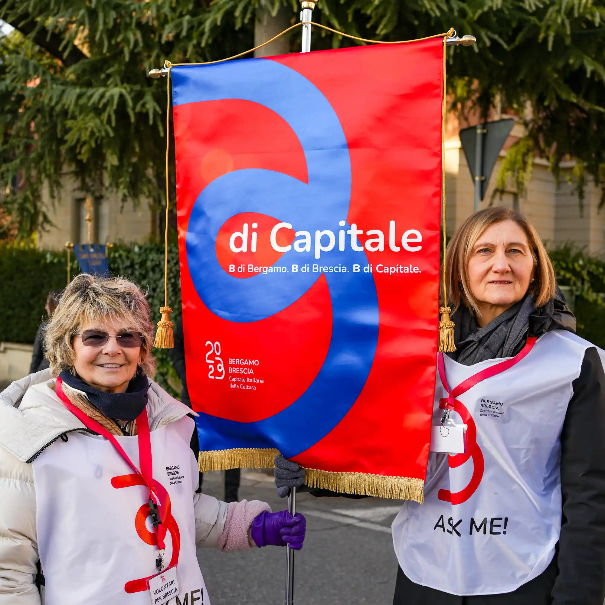 Two women standing next to a red and blue sign.