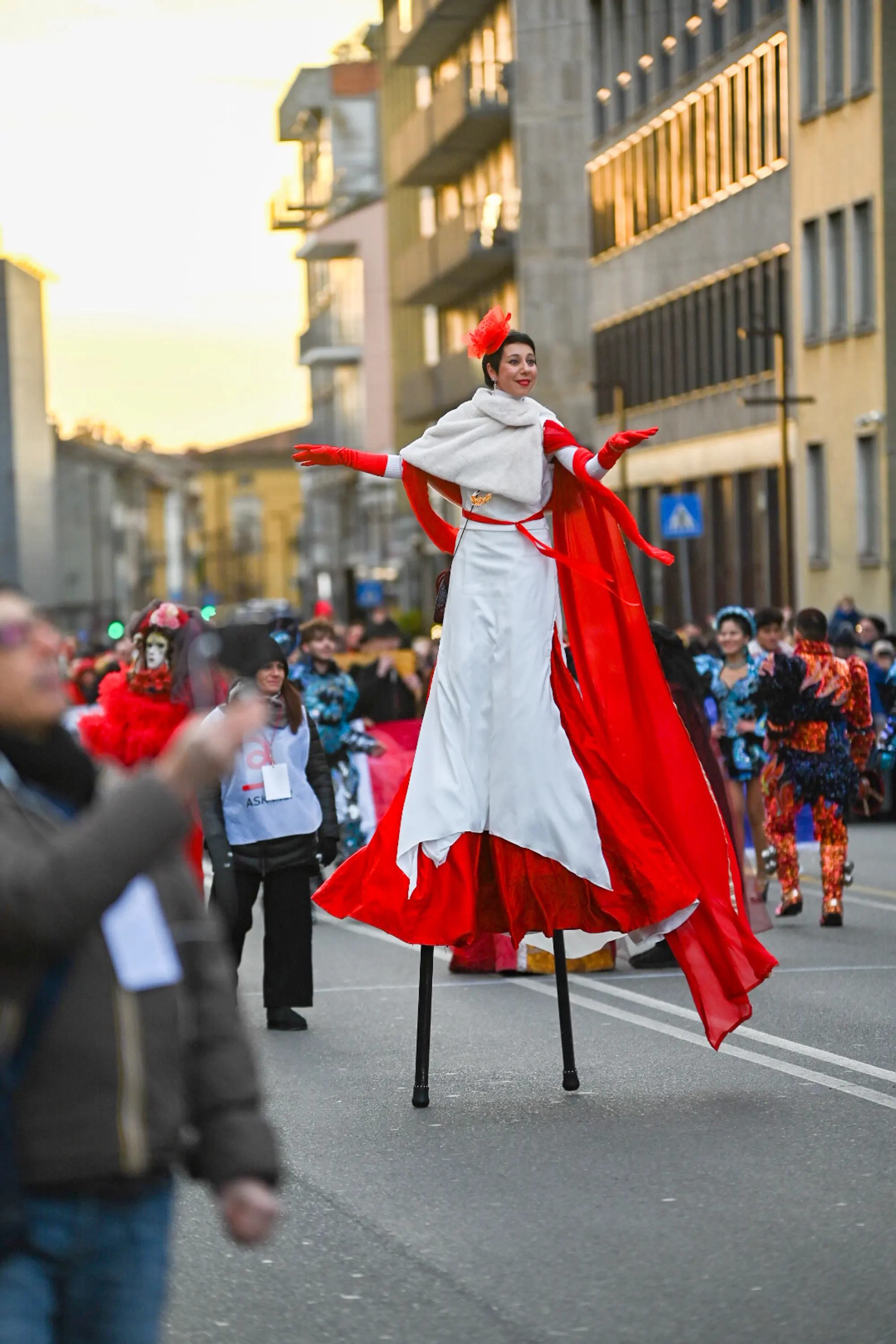 A woman in a red and white dress is standing on a pole.